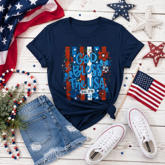 Tea-Shirt Shoppe navy blue graphic tee with "God Bless The USA" text, floral accents, and red, white, and blue stripes.