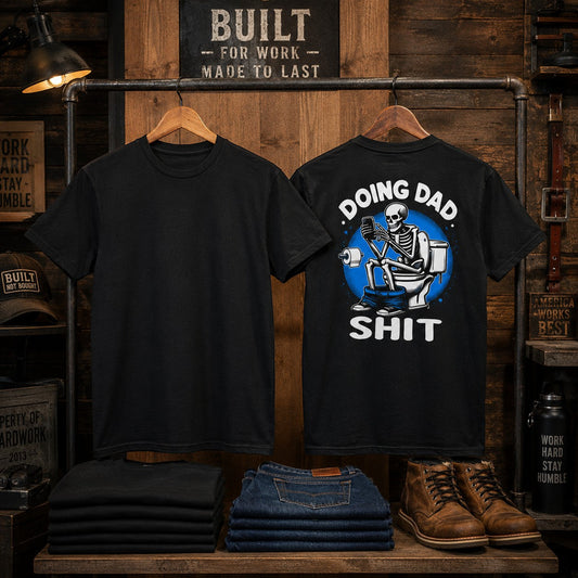 Tea Shirt Shoppe Wholesale black graphic tee with skeleton on toilet reading phone. "Doing Dad Shit" text.
