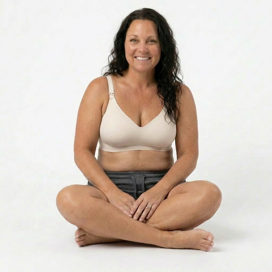 Woman wearing a beige bra sitting cross-legged on a white background