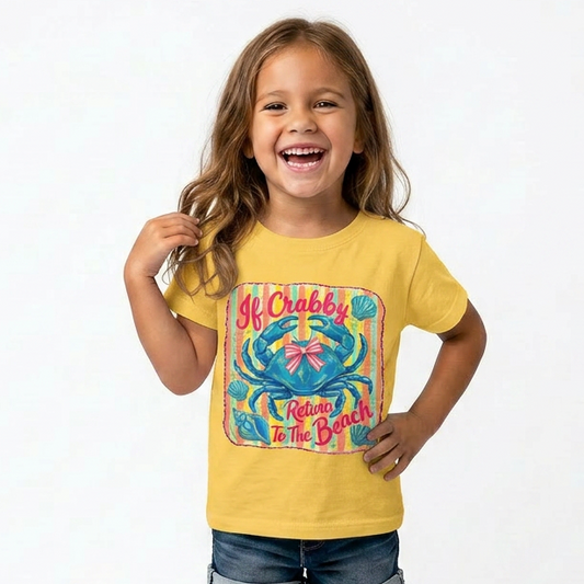 Child wearing a yellow t-shirt with a colorful graphic design that says "If Crabby Return to the beach"