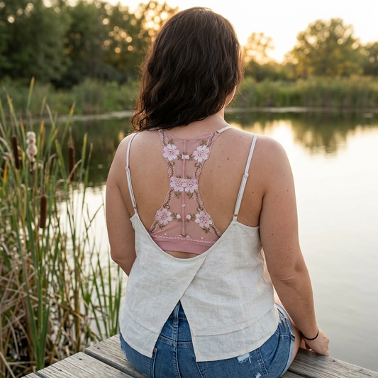 Woman sitting by a lake wearing a floral tank top and white cover-up