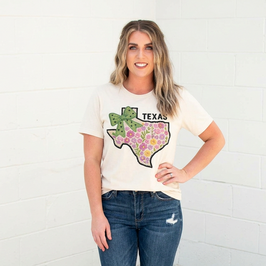 Woman wearing a t-shirt with a floral Texas design and jeans against a white background