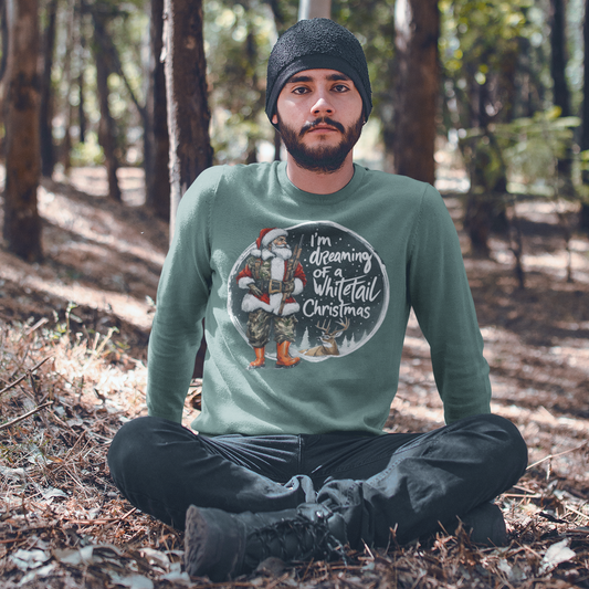 Man sitting in a forest wearing a green sweater with a Christmas design.