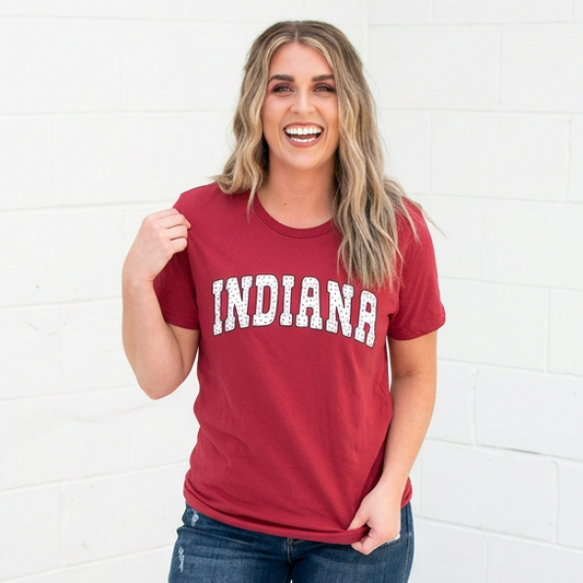 Woman wearing a red 'Indiana' t-shirt and blue jeans against a white background