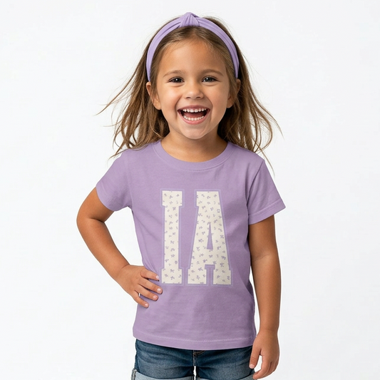 Young girl wearing a purple t-shirt with 'IA' design on a white background