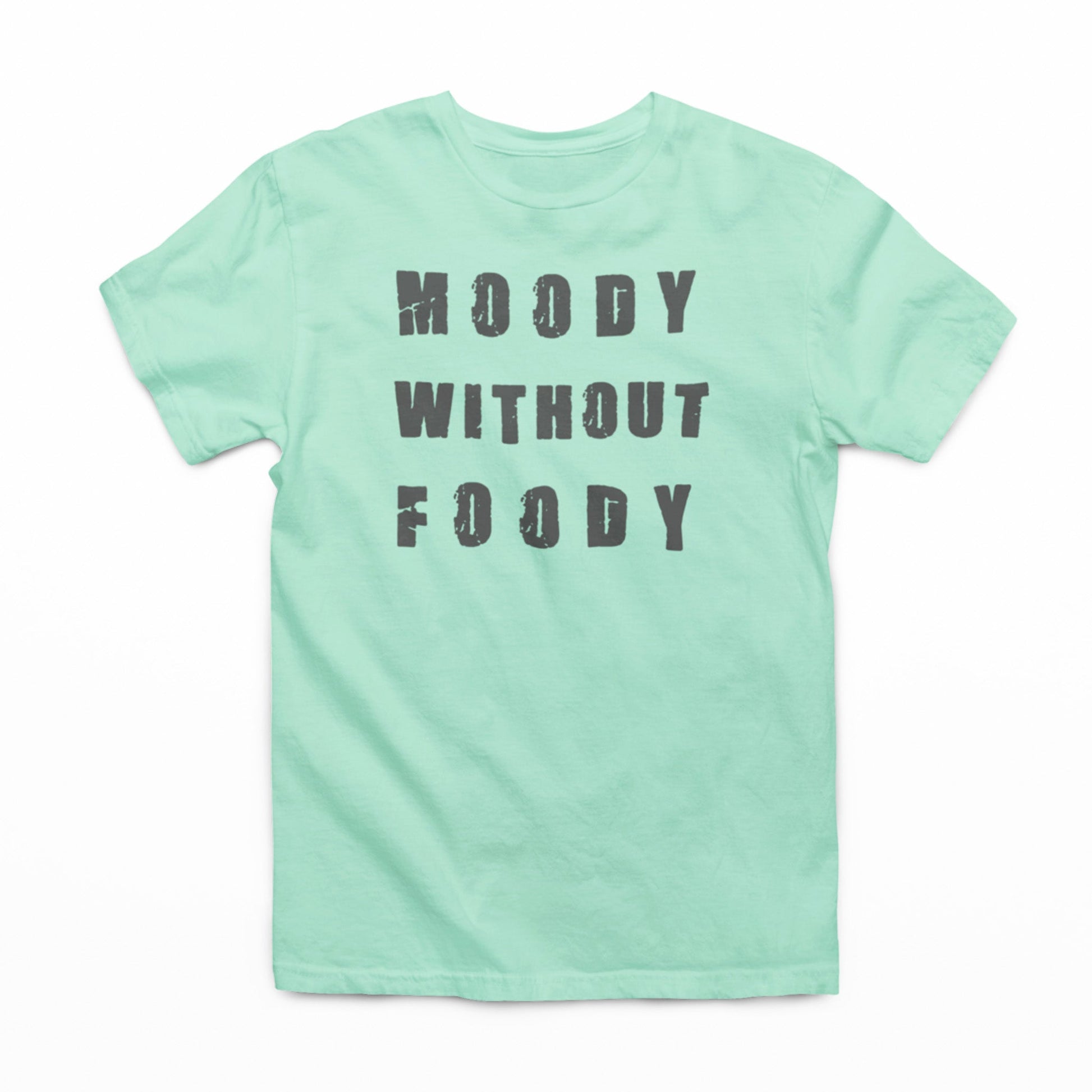 Alt text: "A flat lay of a mint green t-shirt with the phrase 'MOODY WITHOUT FOODY' in bold, distressed grey letters centered on the front. The t-shirt is displayed on a plain white background, highlighting the statement print."