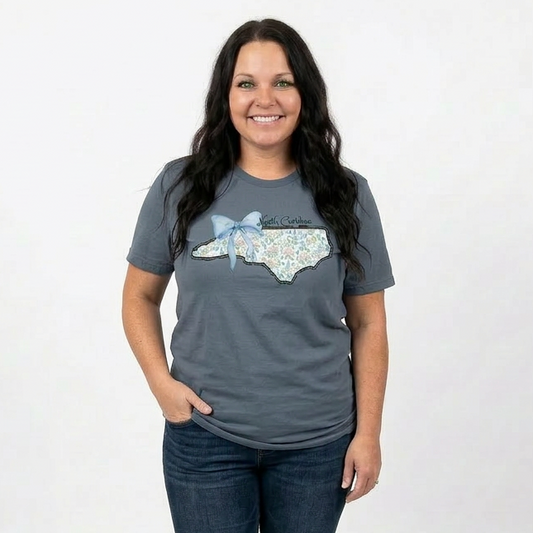 Woman wearing a indigoy t-shirt with a North Carolina design on a white background