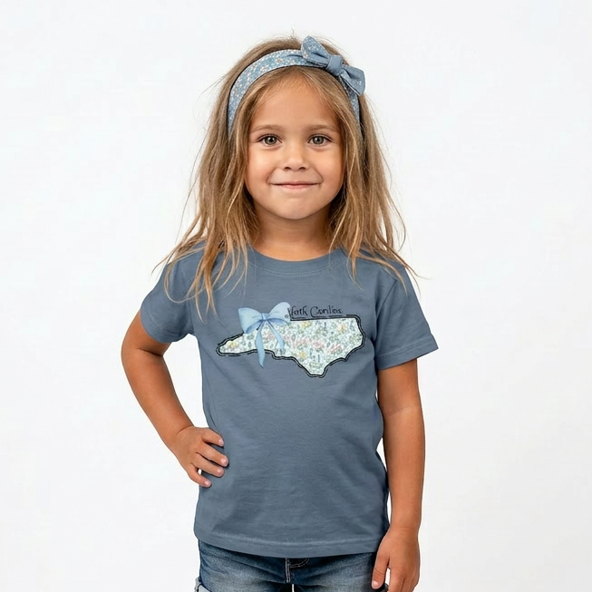 Young girl wearing a blue t-shirt with a North Carolina graphic design on a white background