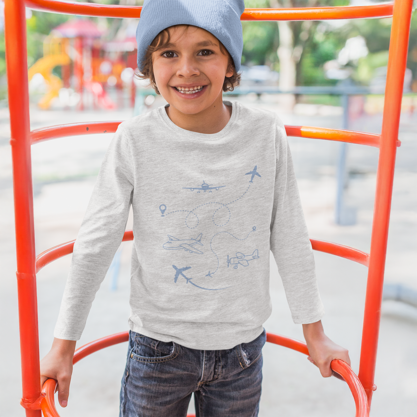 Child wearing a gray sweater with airplane patterns on a playground.