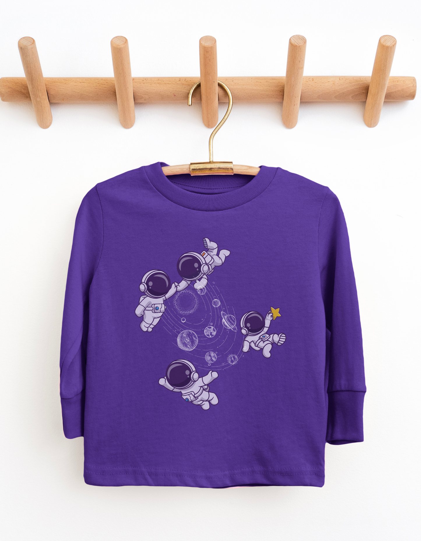 Purple long-sleeve shirt with astronaut design on a wooden hanger against a white background