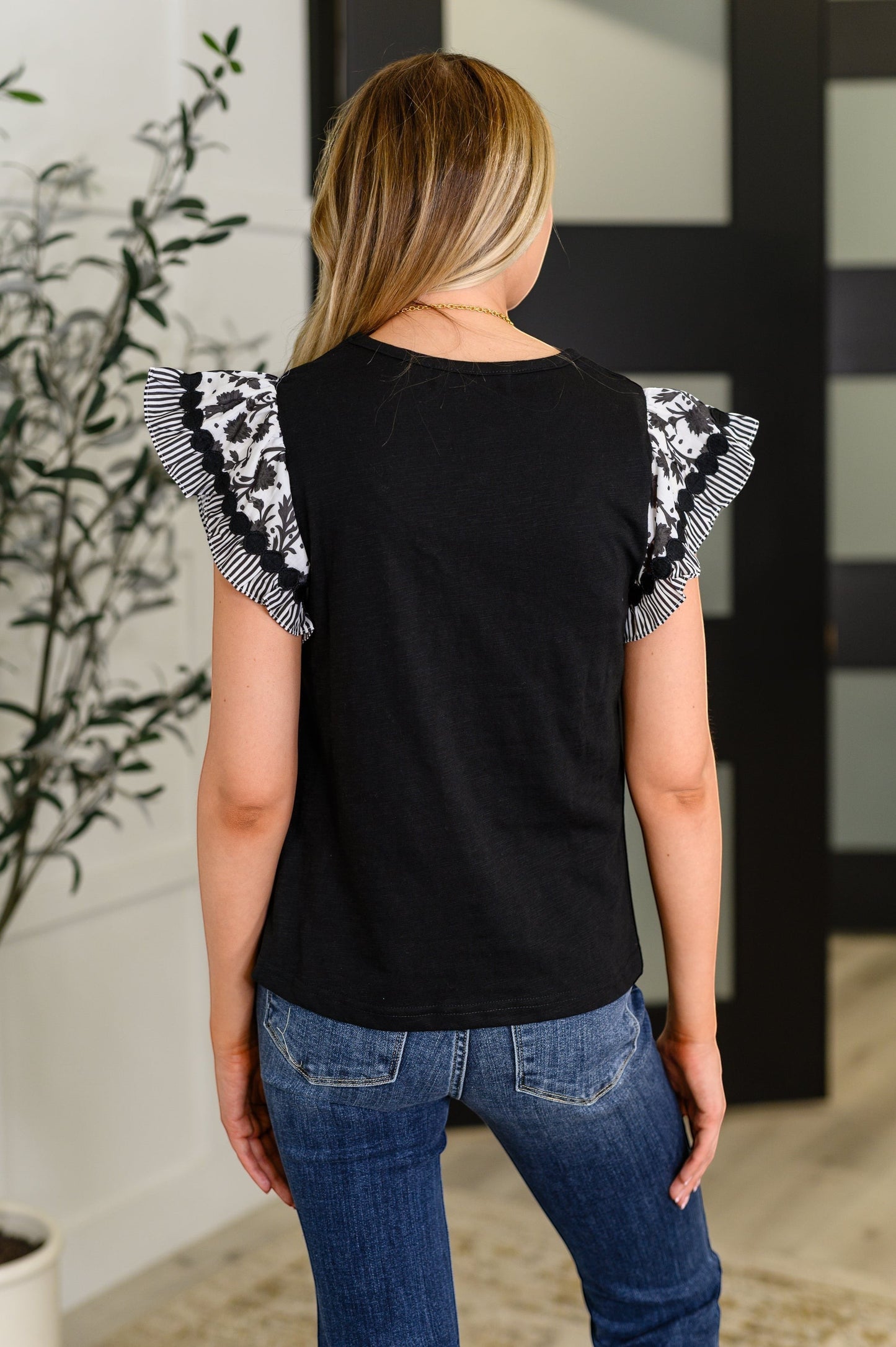 Tea-Shirt Shoppe black top with patterned flutter sleeves and ribbed knit bodice worn with blue jeans