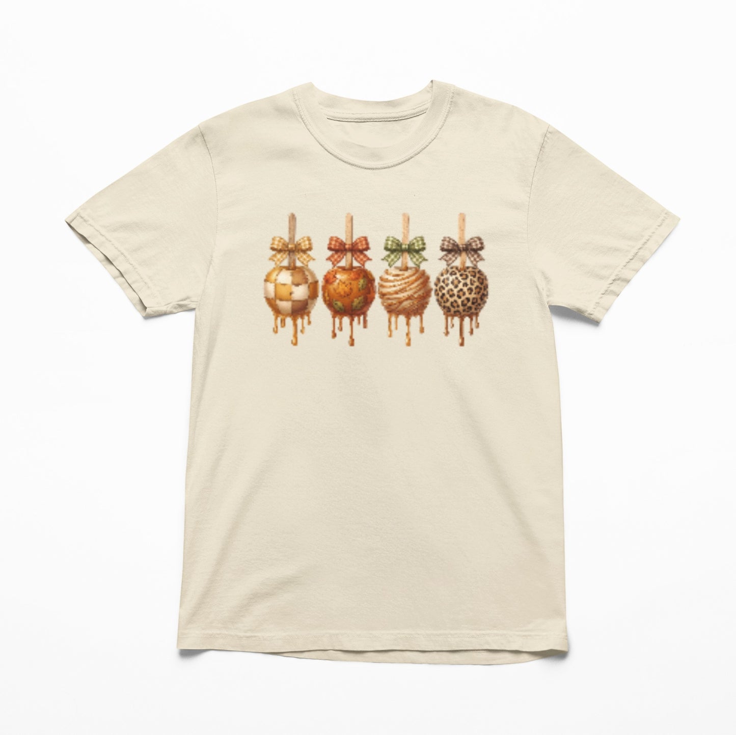 Tea-Shirt Shoppe cream youth graphic tee featuring four caramel apples with checkered, leopard, and autumn patterns.