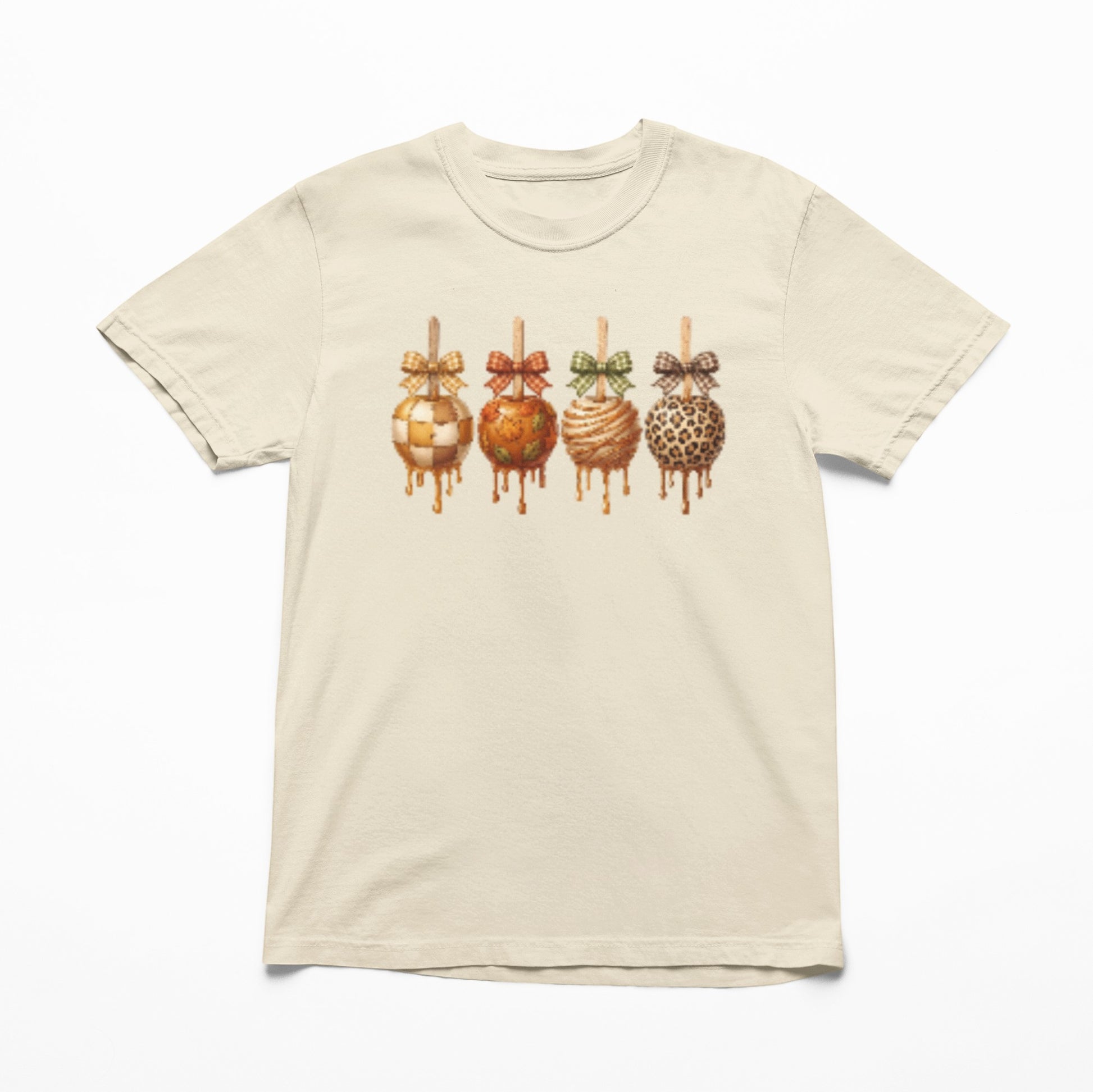 Tea-Shirt Shoppe cream graphic tee featuring four caramel apples with plaid bows in a cozy autumn style.