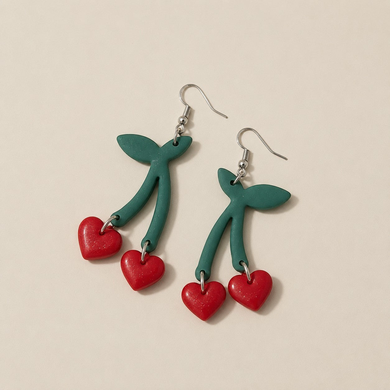 Tea-Shirt Shoppe handcrafted clay heart cherry earrings with green stems and leaves.
