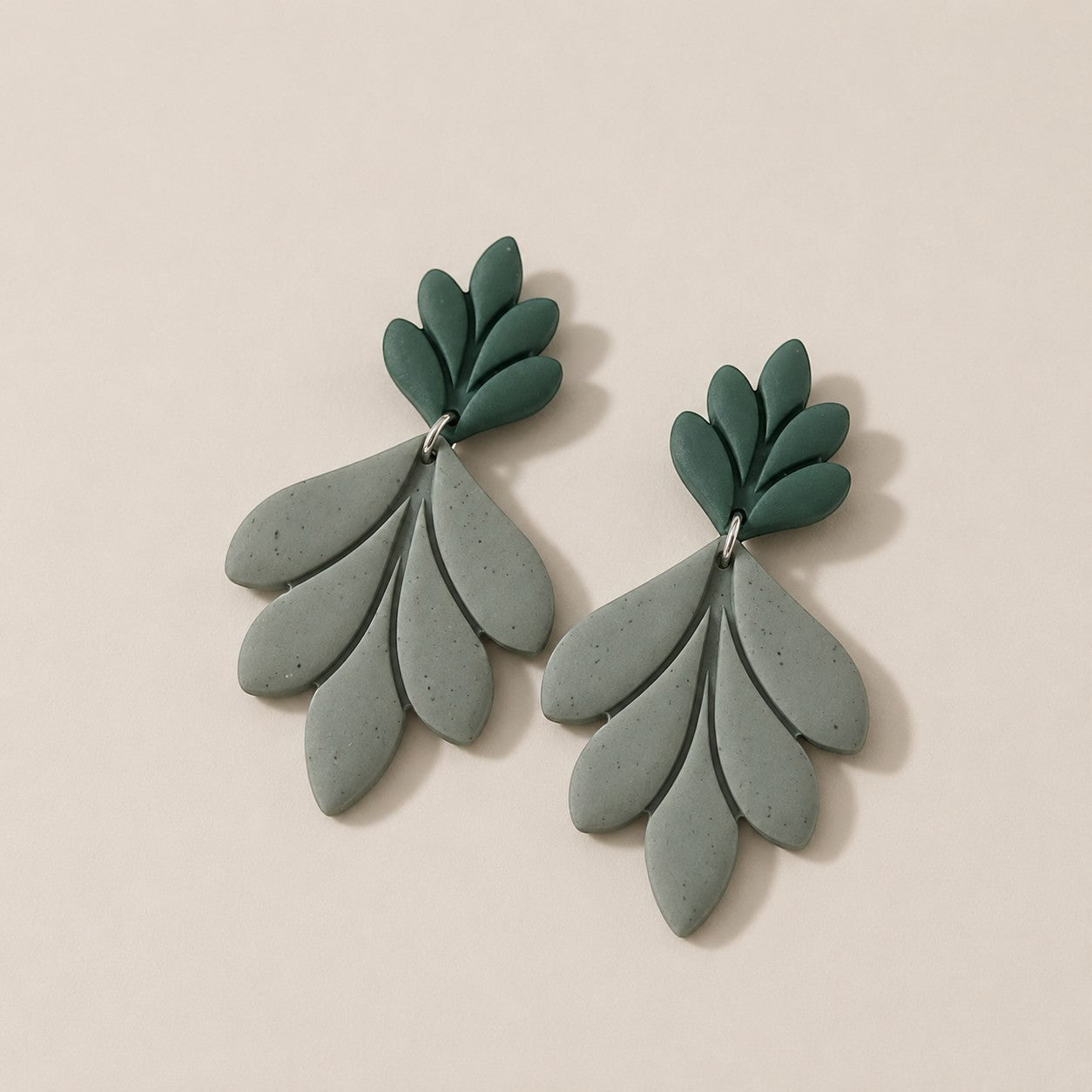 Tea-Shirt Shoppe handcrafted clay earrings with layered leaf design in sage green and muted green.
