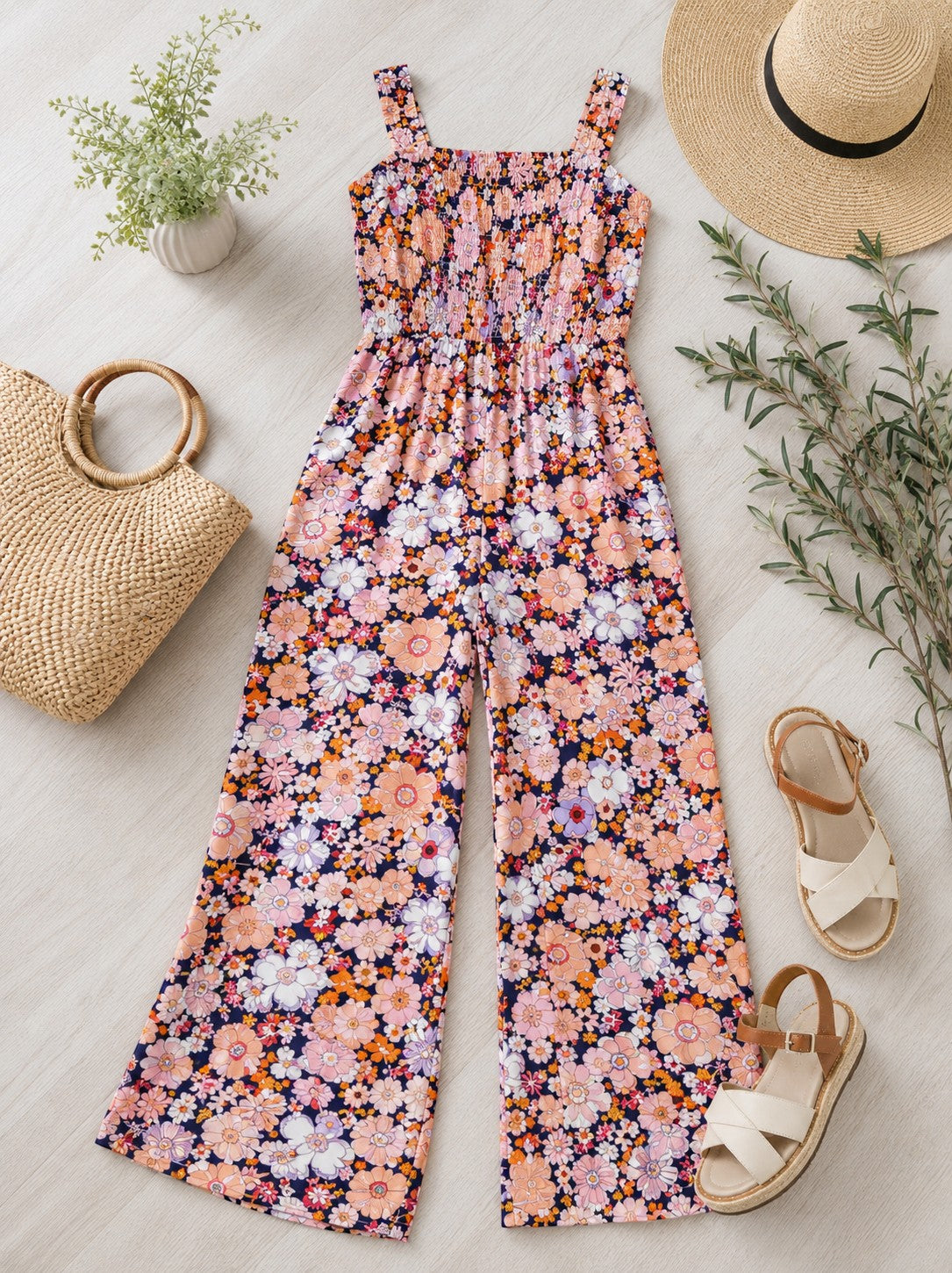Tea-Shirt Shoppe retro floral wide-leg jumpsuit with a smocked bodice and square neckline on a flat lay background.