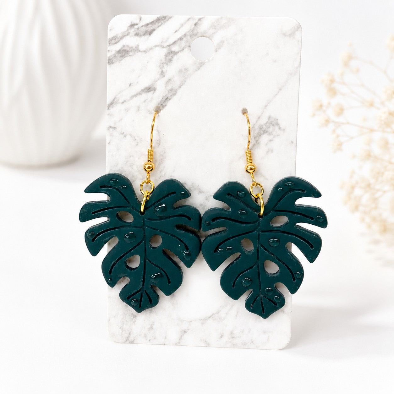Tea-Shirt Shoppe Palm & Petal Collection dark green monstera leaf dangle earrings with gold hooks on marble card