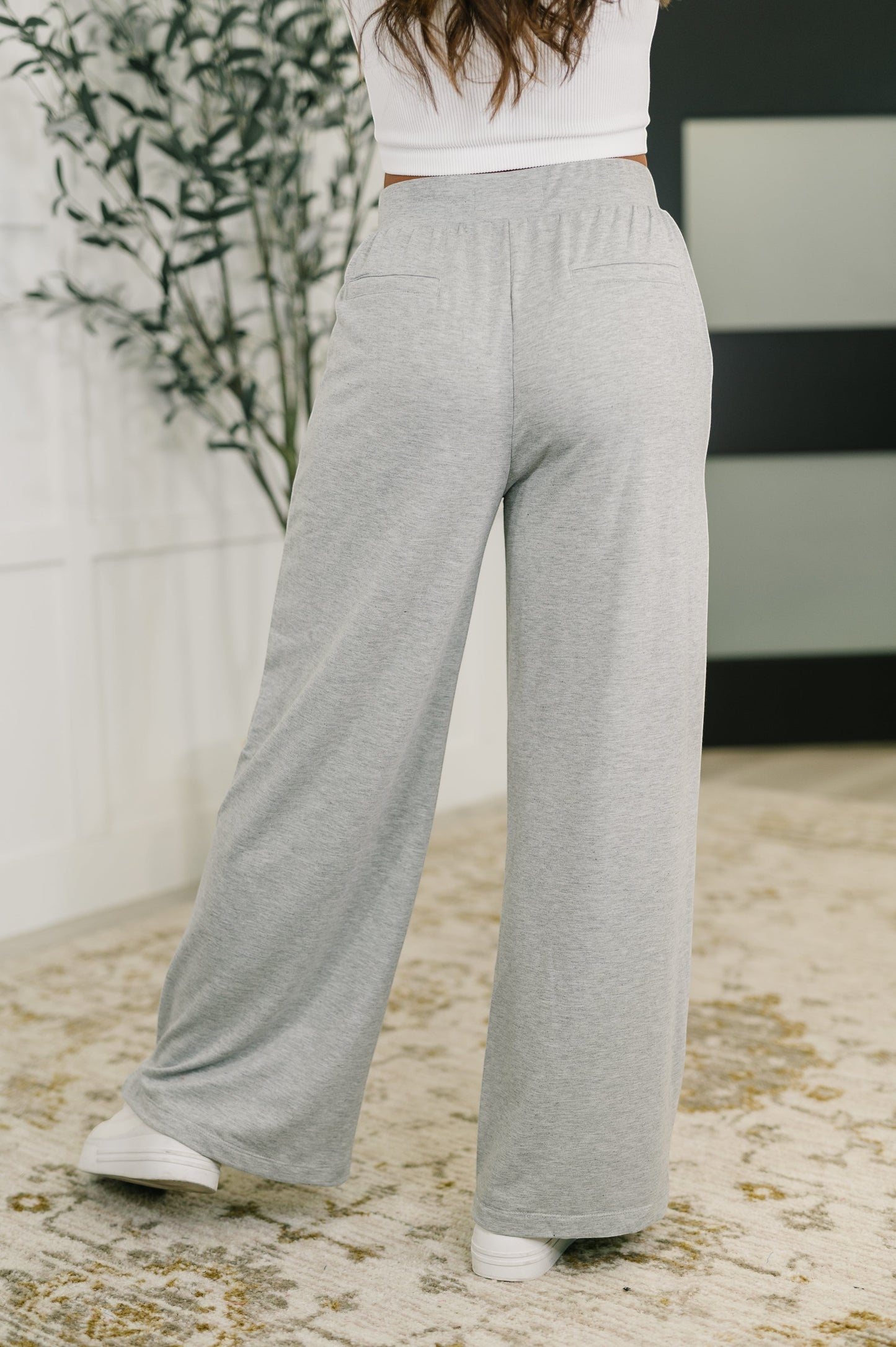 Tea-Shirt Shoppe grey knit wide leg pants with elastic waistband and faux welt pockets worn by a model from behind.