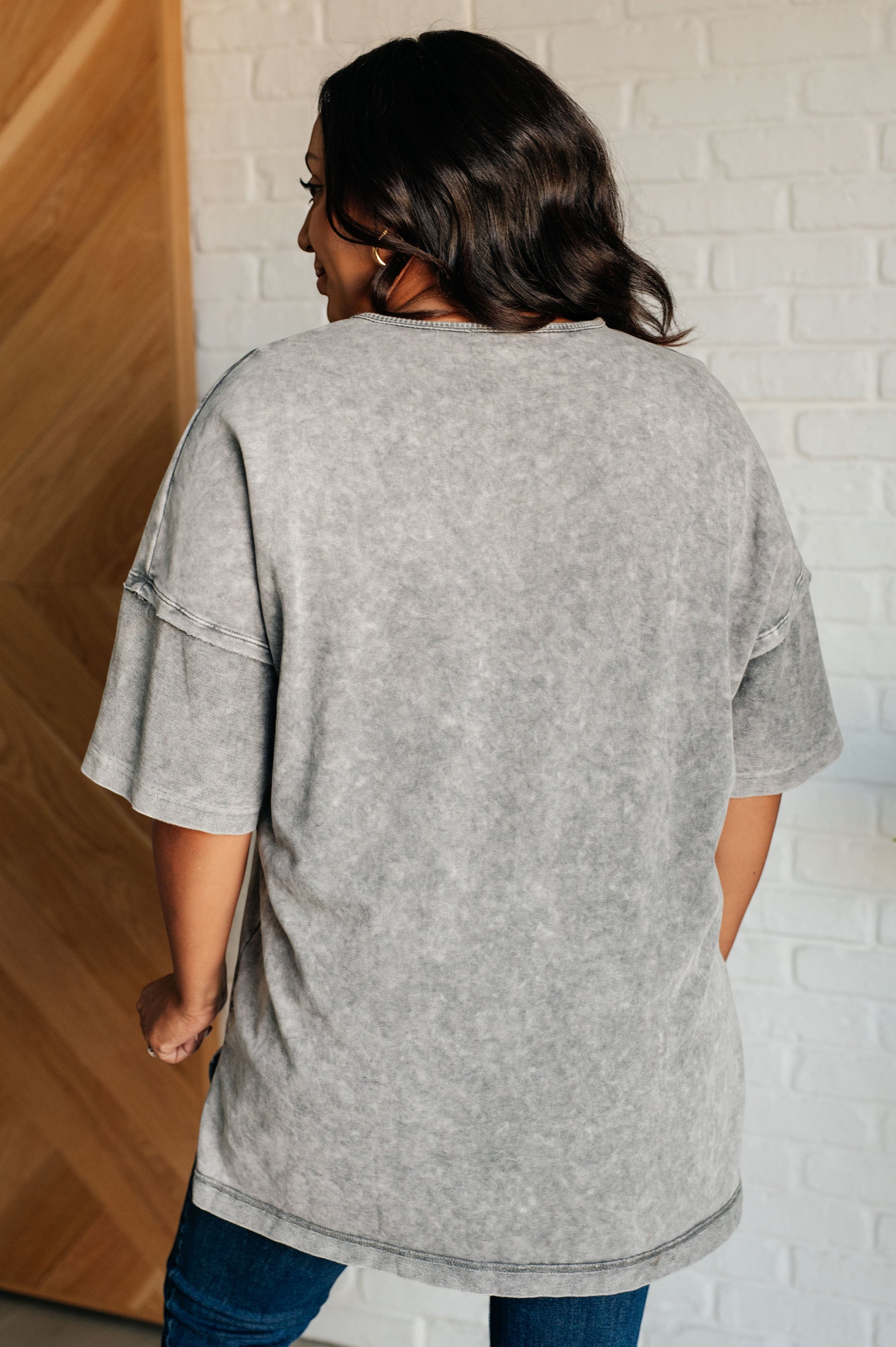 Tea-Shirt Shoppe grey mineral wash top with drop shoulders and raw edge details worn by a model from the back view.