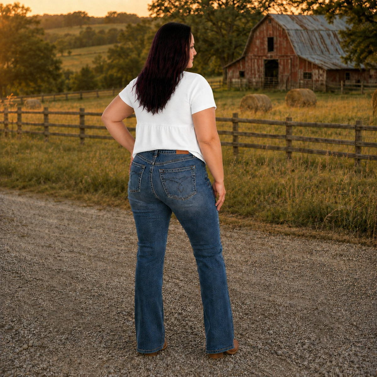 Tea-Shirt Shoppe Judy Blue dark wash high-waist bootcut jeans with tummy control, worn by a woman in a rural setting.