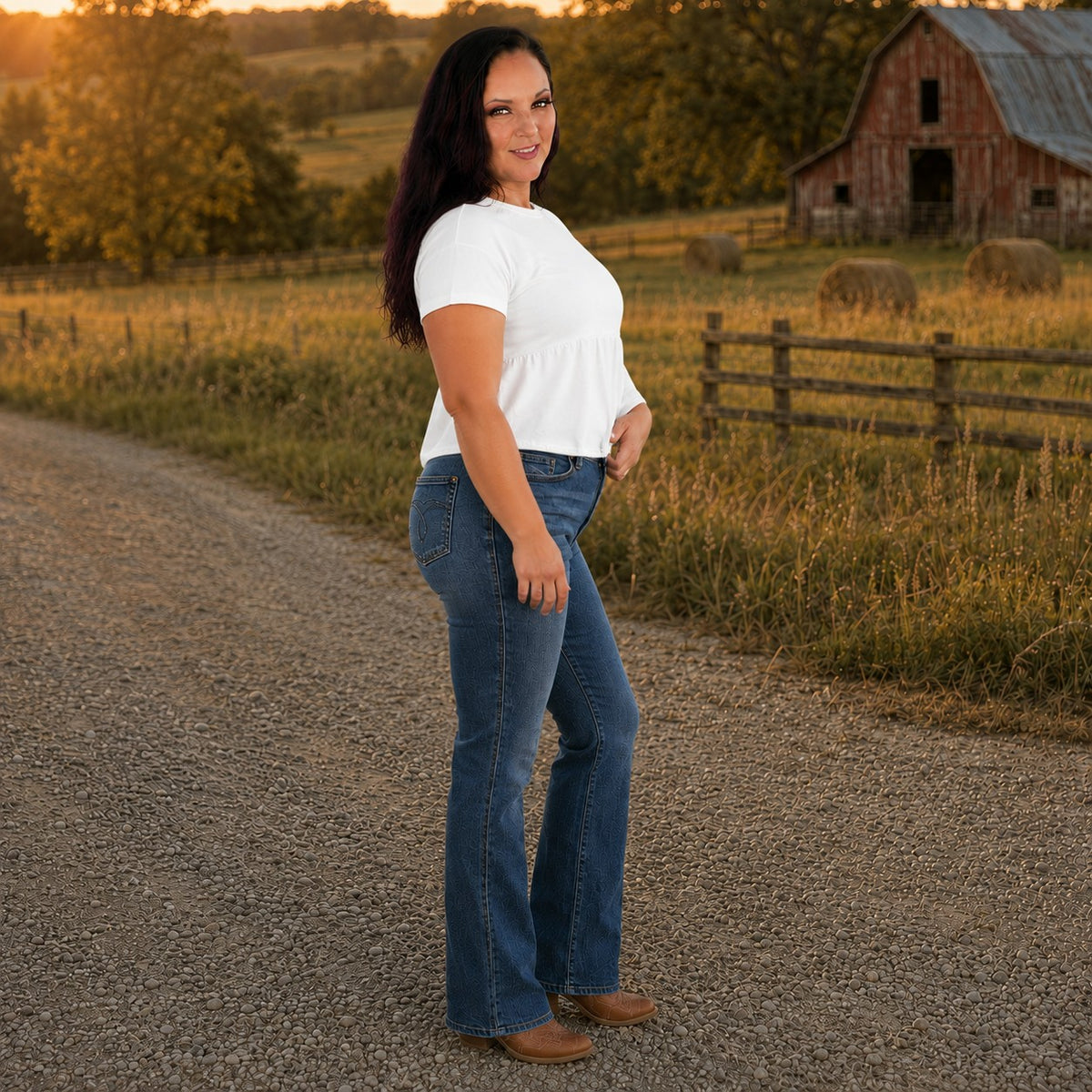 Tea-Shirt Shoppe model wearing Judy Blue dark wash high-waist bootcut jeans with tummy control in a rural field setting