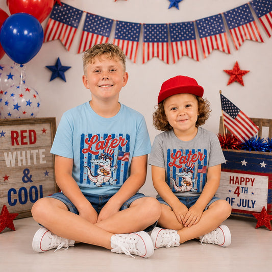 Tea-Shirt Shoppe youth graphic tee in light blue with a patriotic alligator graphic. Two boys sitting.