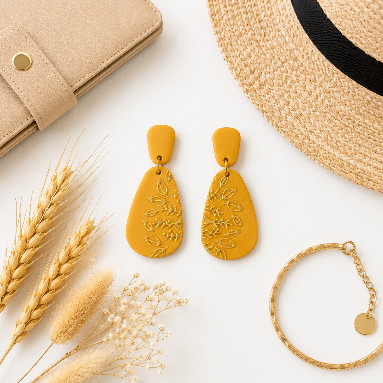 Tea-Shirt Shoppe mustard yellow teardrop dangle earrings with embossed botanical leaf patterns on a white background.