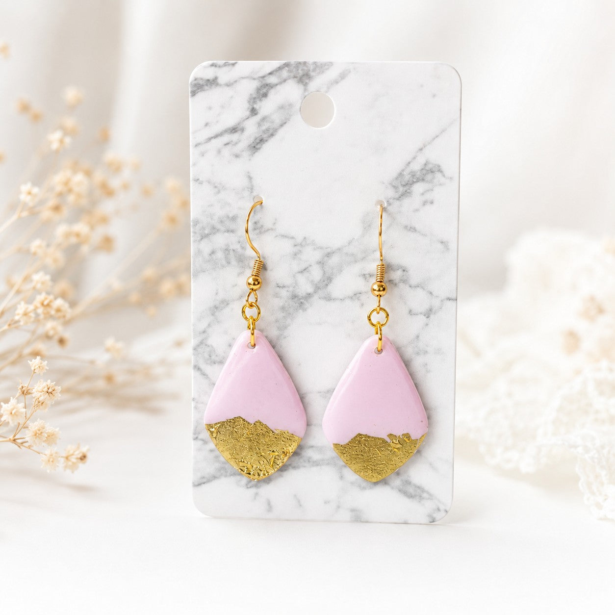 Tea-Shirt Shoppe Palm & Petal Collection pink and gold leaf teardrop clay earrings on a marble display card