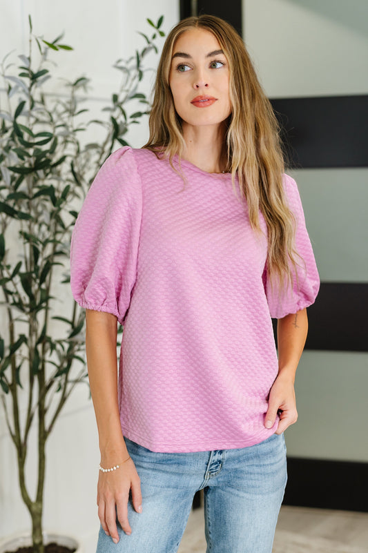 Tea-Shirt Shoppe pink textured knit blouse with puff sleeves and round neckline worn by a model with blue jeans
