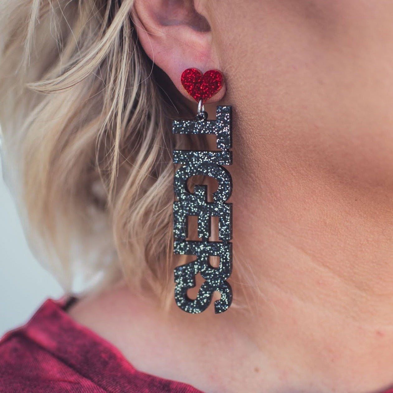 Tea-Shirt Shoppe I Love Tigers drop earrings featuring black glitter text and a red glitter heart on a blonde model.