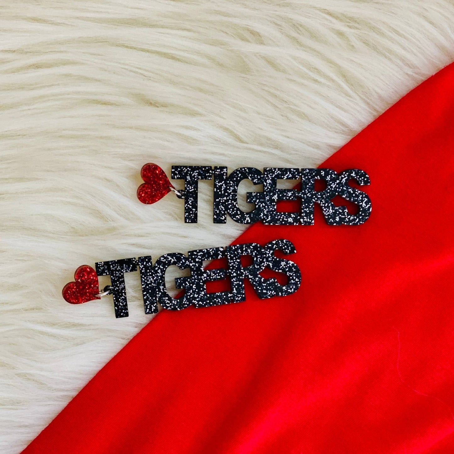 Tea-Shirt Shoppe I Love Tigers drop earrings with black glitter text and red glitter heart accents on white fur.