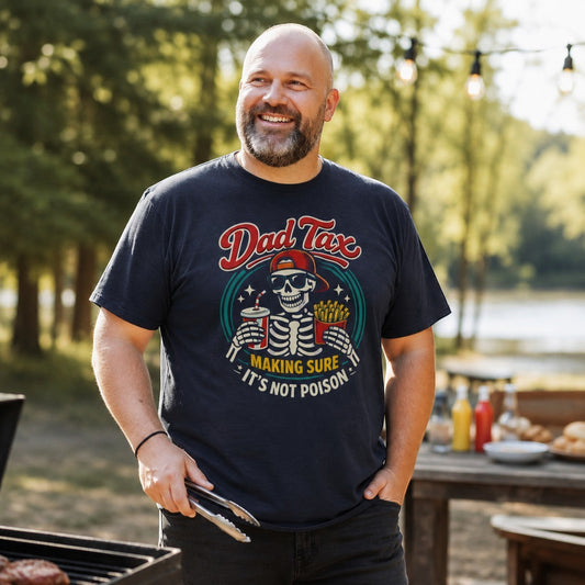 Navy blue cotton graphic tee from Tea Shirt Shoppe Wholesale with a skeleton wearing sunglasses and a red cap, holding fries and a drink. Text reads "Dad Tax: Making Sure It's Not Poison."