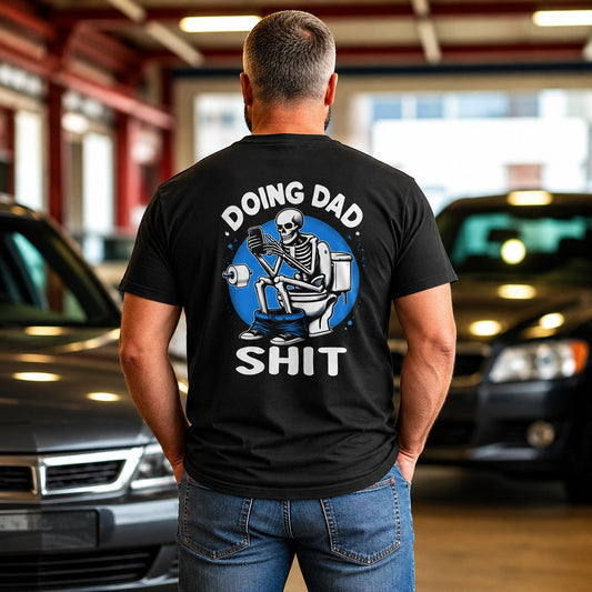 Tea Shirt Shoppe Wholesale black graphic tee with skeleton on toilet reading phone, "Doing Dad Shit" text.