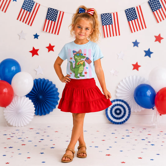 Tea Shirt Shoppe Wholesale light blue 100% cotton graphic tee with a cartoon alligator wearing sunglasses and holding a hot dog and American flag.