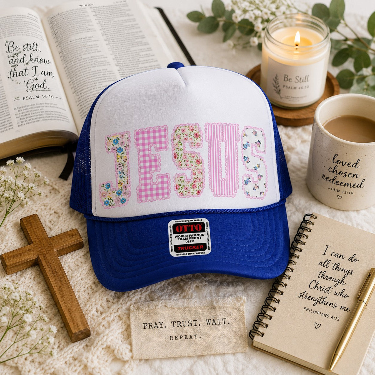 Tea Shirt Shoppe Wholesale blue and white trucker hat with "JESUS" in floral and gingham patchwork letters.