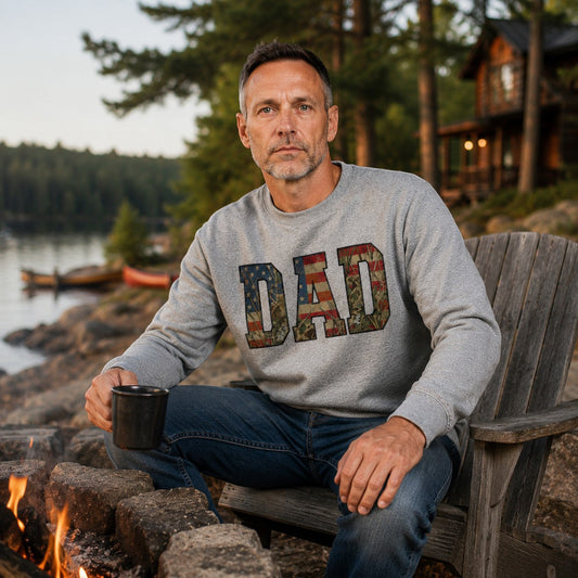Heather grey crewneck sweatshirt with "DAD" graphic featuring American flag and camouflage patterns. Tea Shirt Shoppe Wholesale.