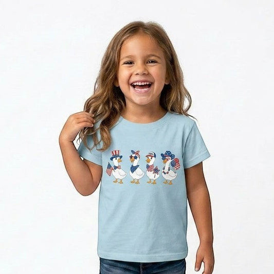 Tea Shirt Shoppe Wholesale light blue graphic tee with four patriotic ducks wearing hats and bandanas, a girl models the shirt.