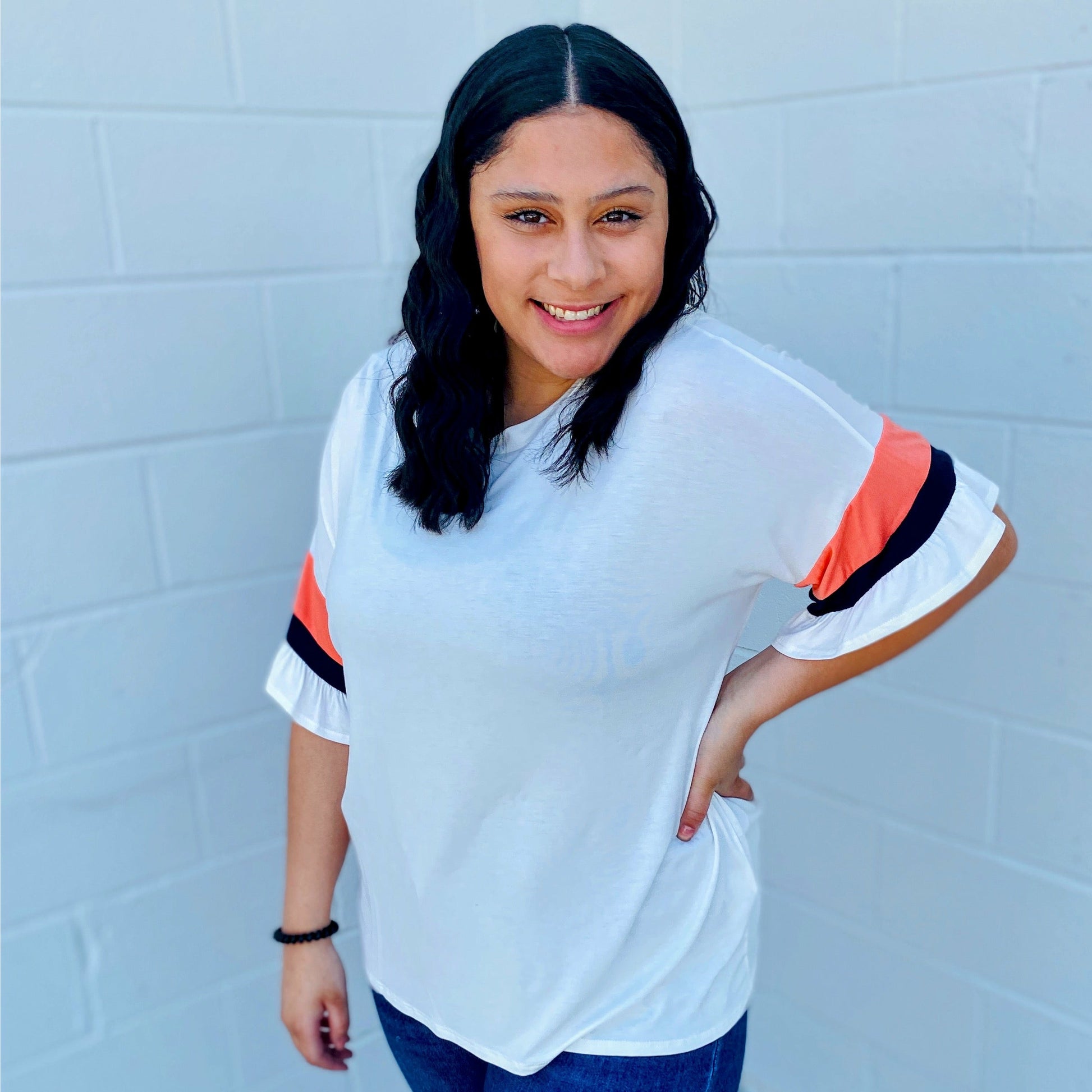 We all agree we love the sleeves on this top. Just the right amount of color detail. The navy and coral stripes on the sleeves really pop on the white base. This top features a round neck for comfort and ruffled sleeves in a soft jersey material.