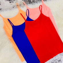 flatlay of four bright colored tanks
